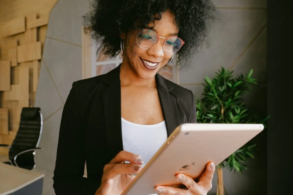 pexels-photo-3727457 Smiling woman using a tablet in a modern office setting, showcasing technology and business.