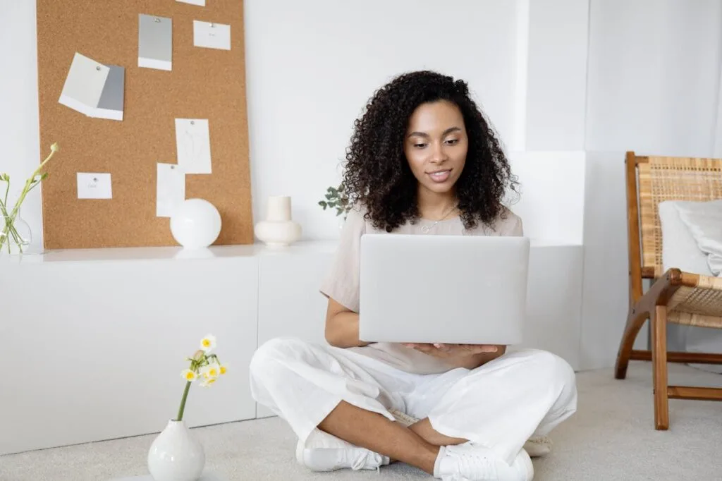 pexels-photo-7552374 Young woman with curly hair working on her laptop in a cozy home setting, exuding confidence and focus.